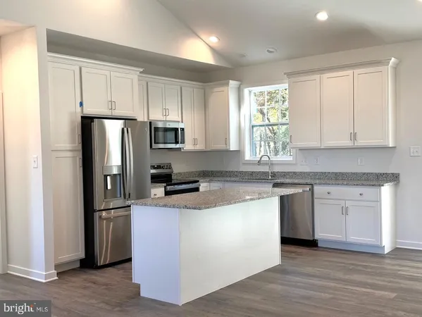 a kitchen with stainless steel appliances granite countertop a refrigerator a stove a sink and white cabinets