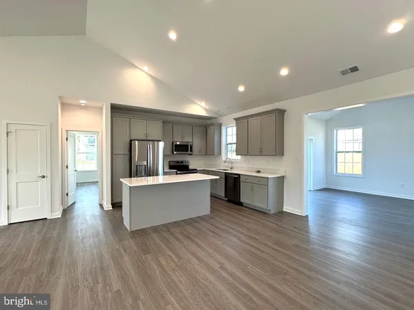 a large kitchen with a center island and wooden floor