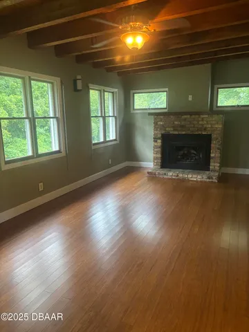 an empty room with wooden floor fireplace and windows