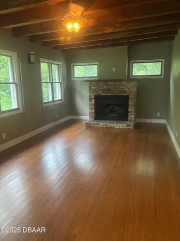 an empty room with wooden floor a fireplace and windows