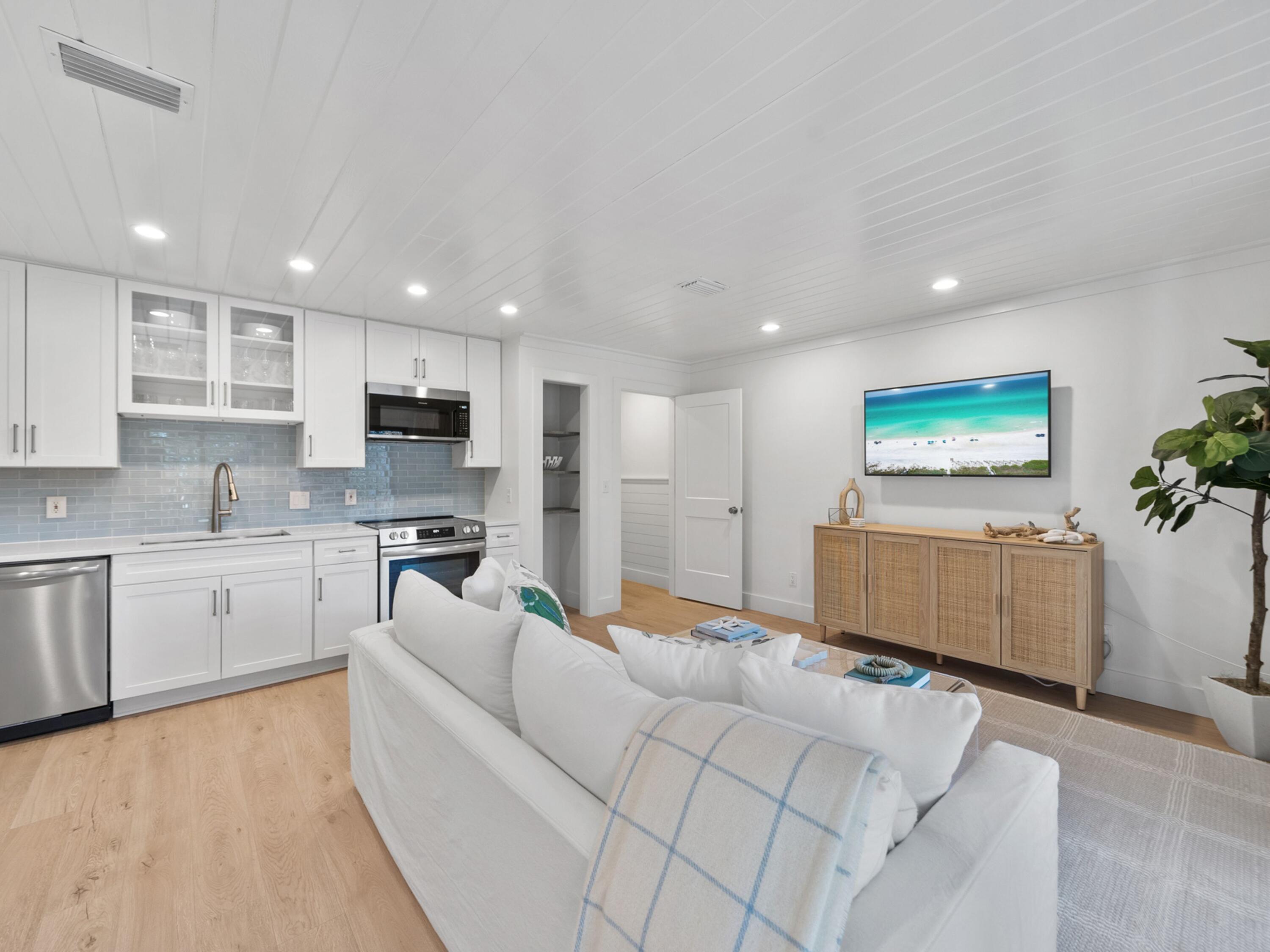 81 South Orange Street, Unit 205 Inlet Beach, FL 32461 - Photo 14 of 28 a large white kitchen with kitchen island a sink dishwasher a stove a refrigerator and white cabinets with wooden floor