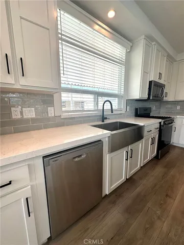 a kitchen with stainless steel appliances granite countertop a sink a stove cabinets and a window