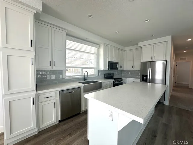 a kitchen with a refrigerator a sink and white cabinets