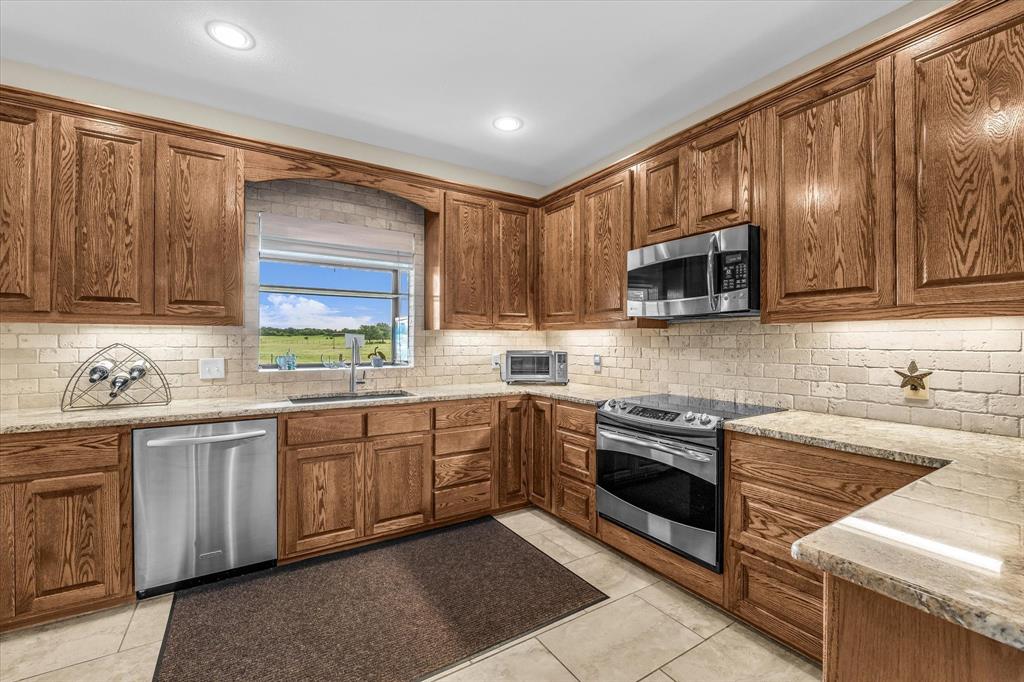 613 Bone Road Valley Mills, TX 76689 - Photo 9 of 40 a kitchen with stainless steel appliances granite countertop a sink and stove top oven