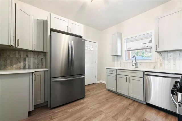 a kitchen with stainless steel appliances granite countertop a refrigerator a sink and white cabinets
