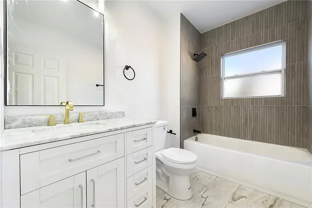 a bathroom with a granite countertop sink a toilet mirror and bathtub
