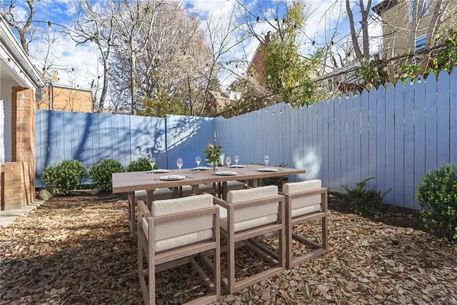 a view of a backyard with table and chairs potted plants and tree