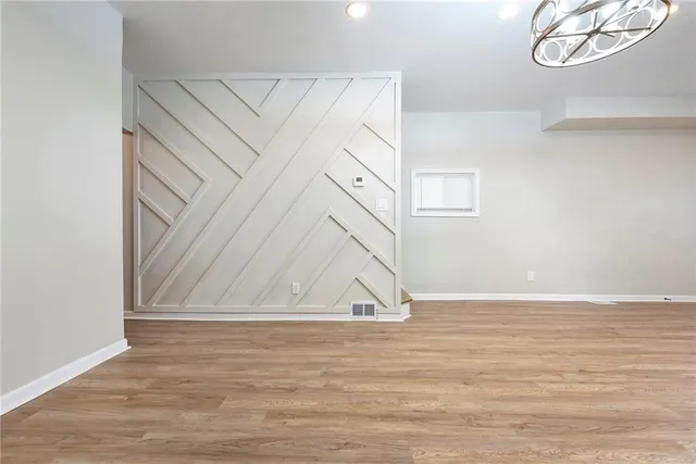 a view of an empty room with wooden floor and fan
