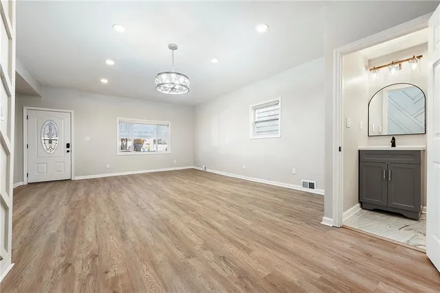 an empty room with wooden floor cabinet and windows