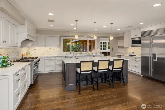 a kitchen with stainless steel appliances granite countertop a table chairs sink refrigerator and cabinets