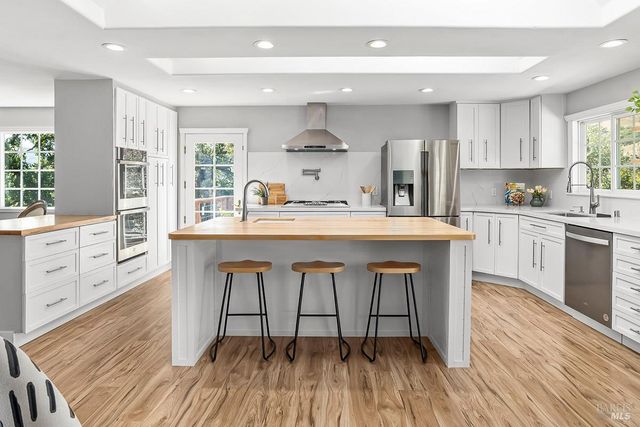 a kitchen with stainless steel appliances a dining table chairs stove refrigerator and cabinets