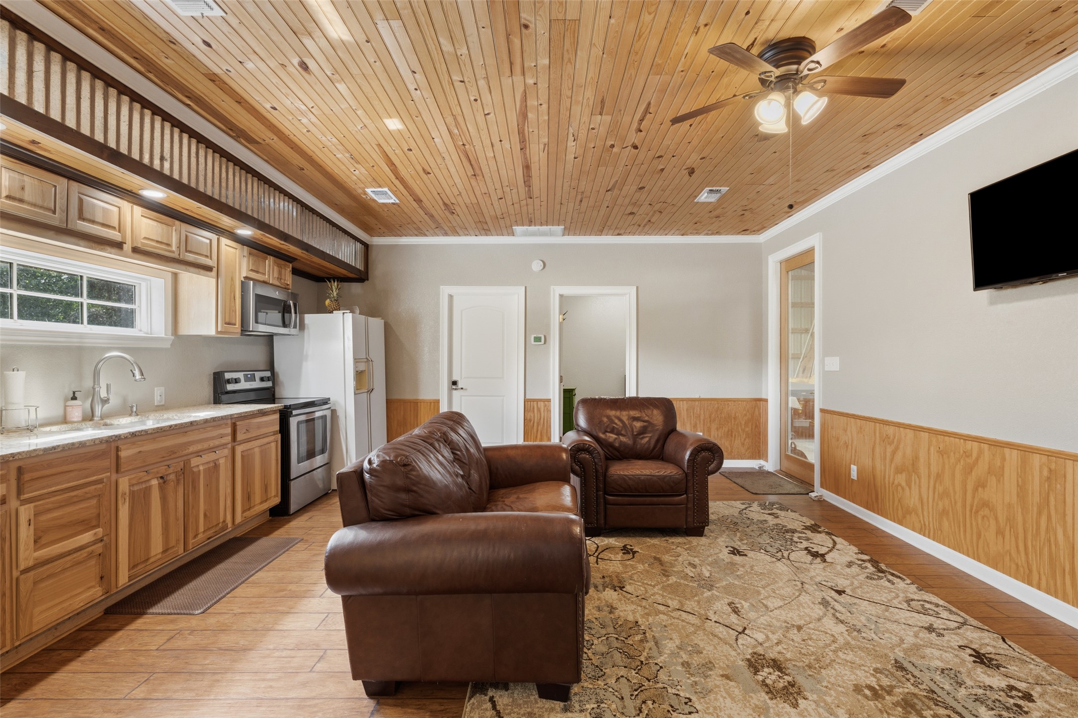 764 Stubbs Road Johnson City, TX 78636 - Photo 8 of 29 A warm, inviting living space features wood plank ceilings, wainscoting, and a compact kitchen area.