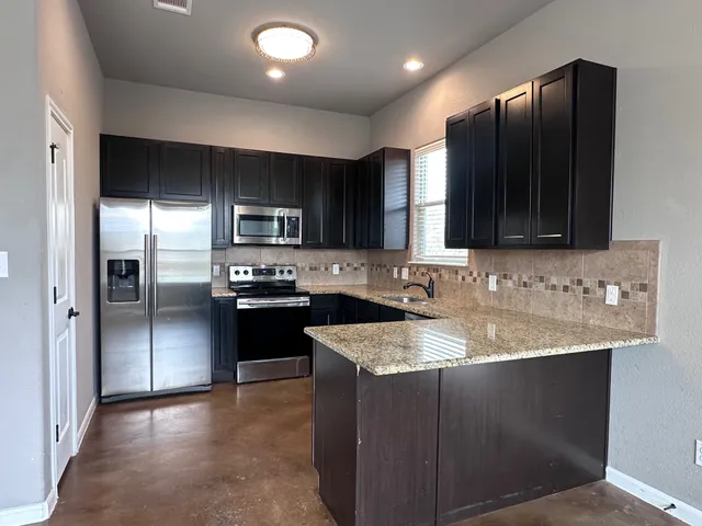 a kitchen with stainless steel appliances granite countertop a refrigerator a sink a stove a microwave and wooden cabinets