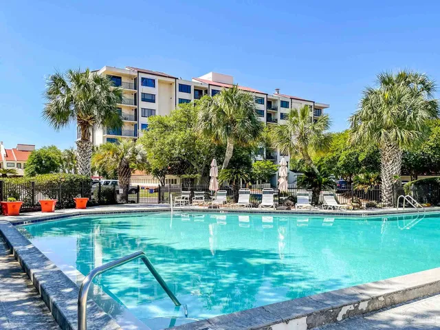 a view of a swimming pool with a bench and trees in the background