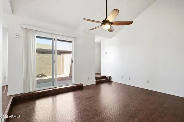 an empty room with wooden floor fan and windows