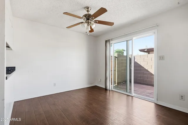 an empty room with wooden floor fan and windows