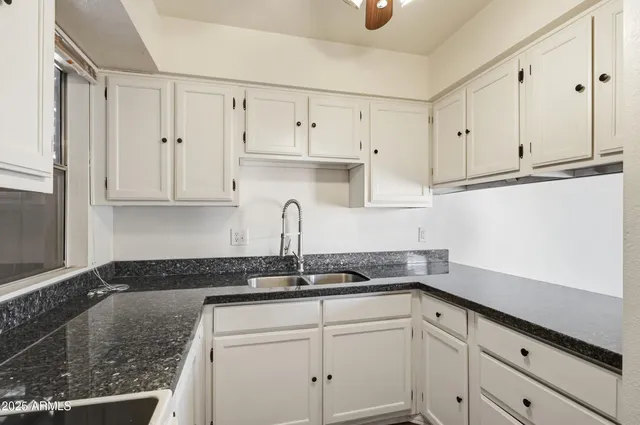 a kitchen with granite countertop white cabinets and white appliances