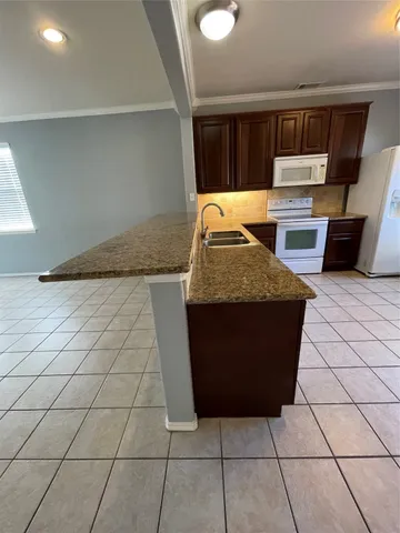a kitchen with granite countertop a stove a microwave a sink and cabinets