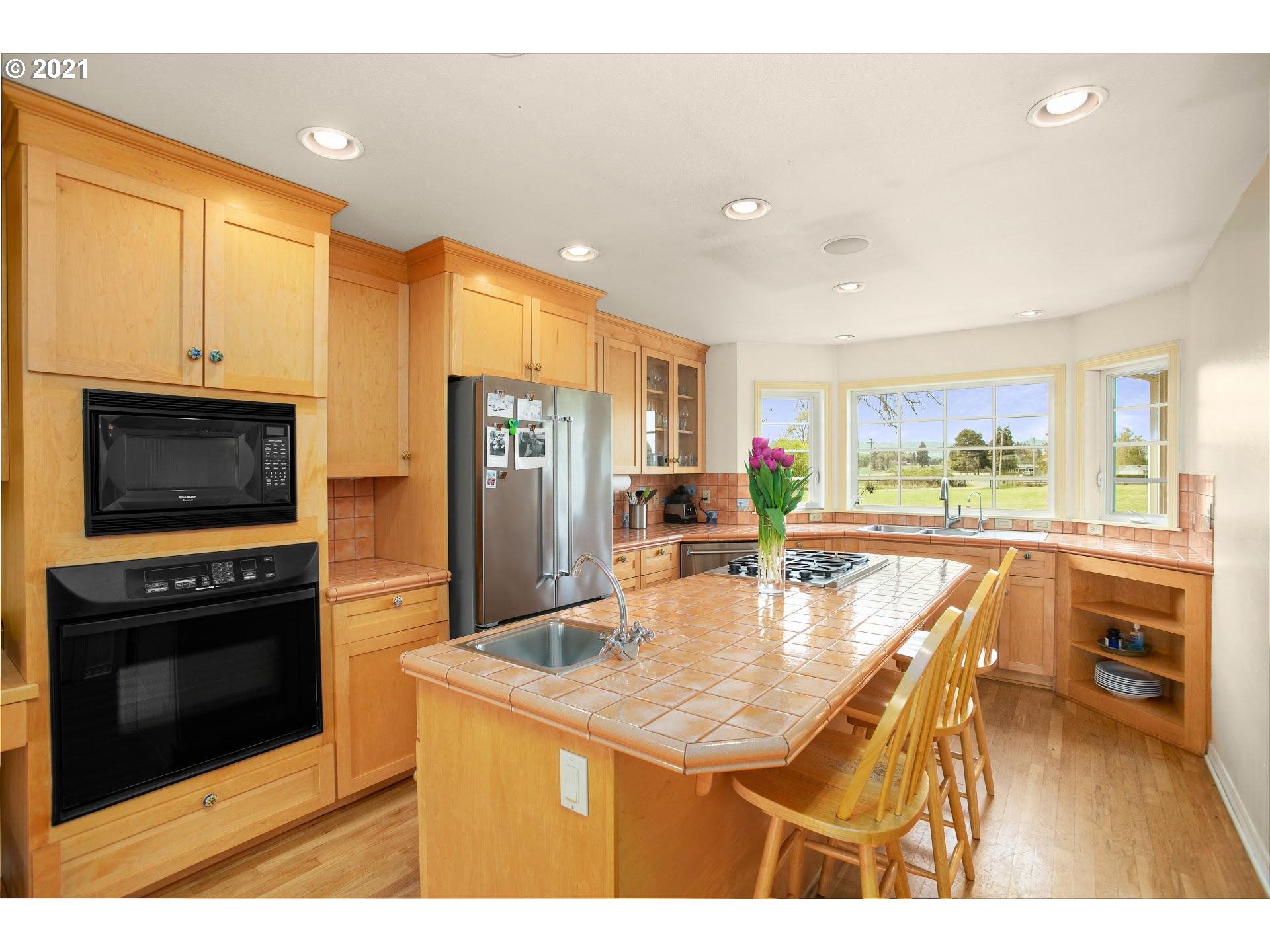 15620 Northwest Gillihan Road Portland, OR 97231 - Photo 7 of 29 a kitchen with stainless steel appliances granite countertop a stove a refrigerator a kitchen island a stove and white cabinets with wooden floor