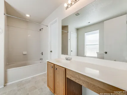 a bathroom with a tub sink and mirror