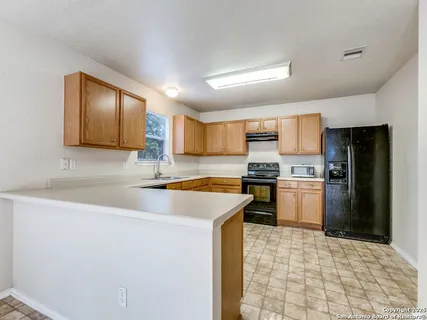 a kitchen with a sink a stove top oven and refrigerator