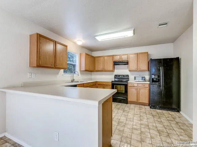 a kitchen with a sink a stove top oven and refrigerator
