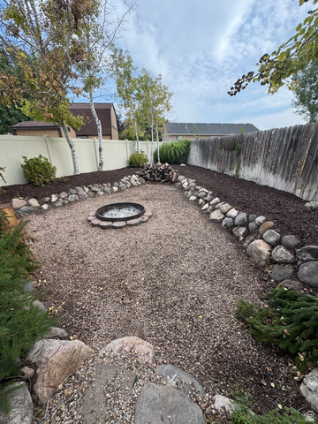 1237 South 260 West Payson, UT 84651 - Photo 19 of 81 Expansive backyard featuring a gravel patio, built-in fire pit, perimeter landscaping with natural rock accents, and mature trees