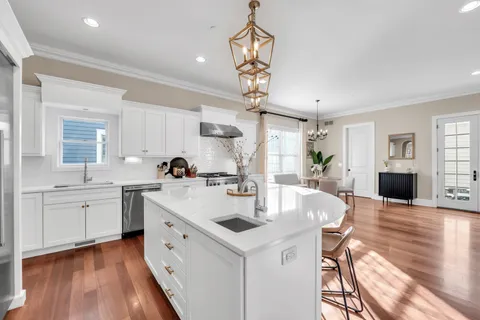 a large kitchen with stainless steel appliances kitchen island granite countertop a stove a sink a dining table and chairs with wooden floor