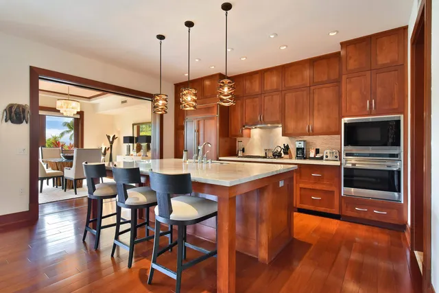 a kitchen with stainless steel appliances granite countertop a stove a sink a microwave a dining table and chairs with wooden floor