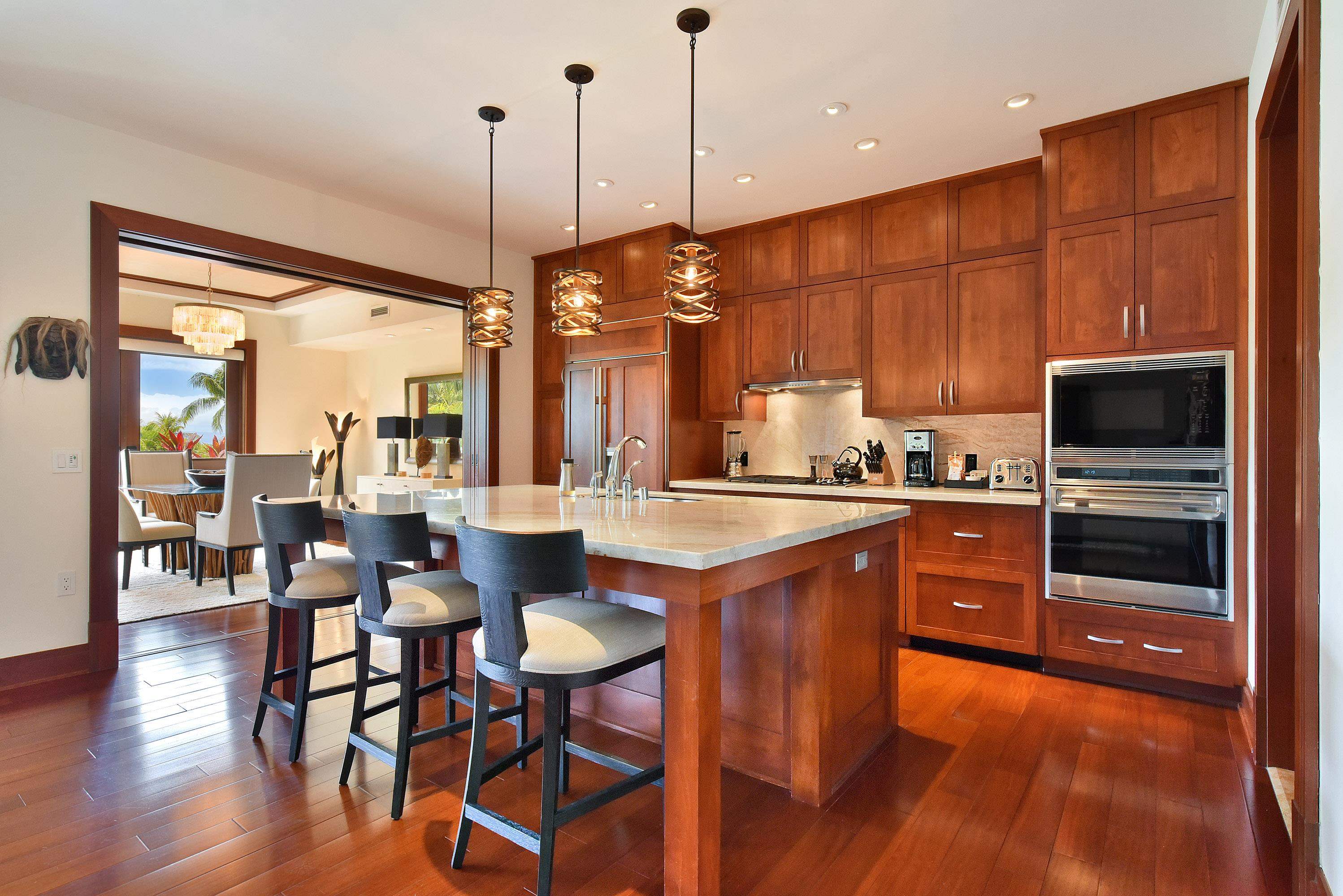 1 Bay Drive, Unit 5102 Lahaina, HI 96761 - Photo 10 of 50 a kitchen with stainless steel appliances granite countertop a stove a sink a microwave a dining table and chairs with wooden floor