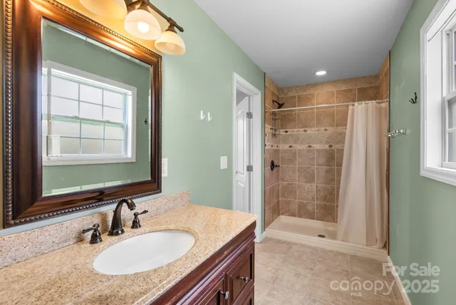 a bathroom with a granite countertop sink a mirror and a shower
