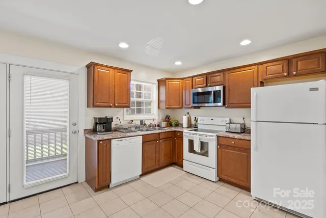 a kitchen with stainless steel appliances granite countertop a stove top oven a sink dishwasher and a refrigerator