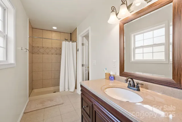 a bathroom with a granite countertop double vanity sink a mirror and a shower