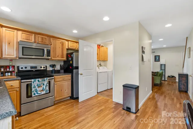 a kitchen with stainless steel appliances granite countertop a stove top oven a sink dishwasher a microwave oven and a refrigerator with wooden floor