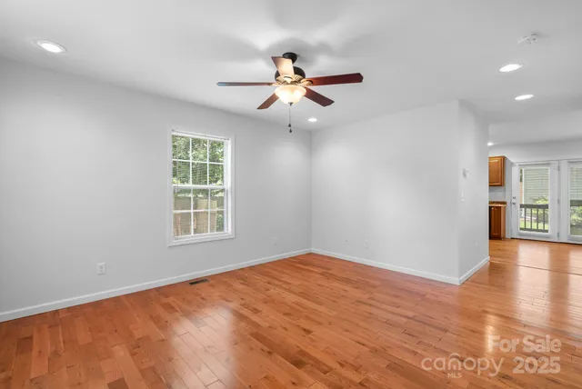 a view of an empty room with a window and wooden floor