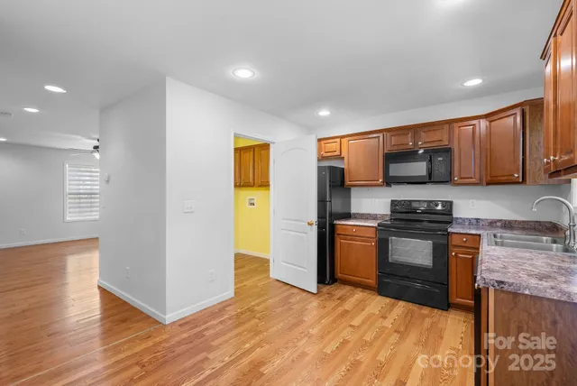 a kitchen with stainless steel appliances granite countertop wooden cabinets a stove a sink and a refrigerator