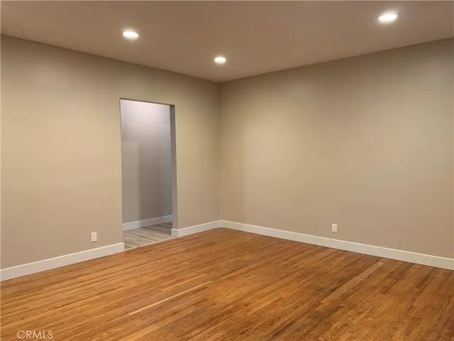an empty room with wooden floor and natural light