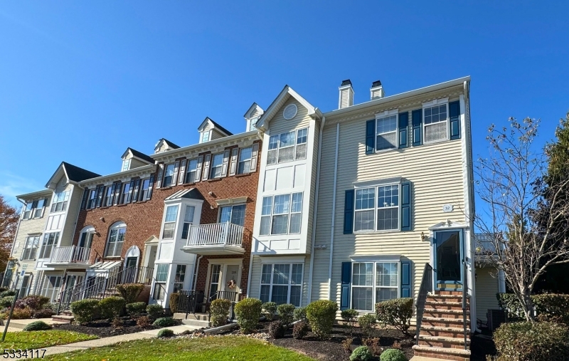 a front view of a building with lot of cars and trees