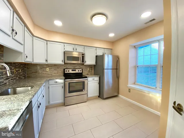 a kitchen with granite countertop a refrigerator and a stove top oven
