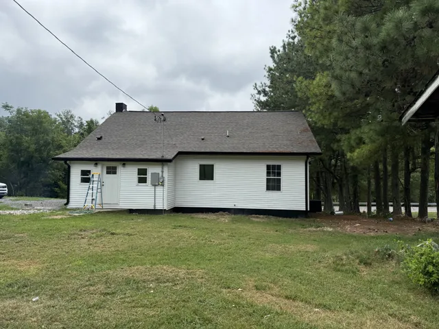 a front view of house with yard and trees in the background