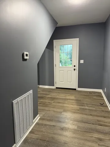 a view of an empty room with wooden floor and a window