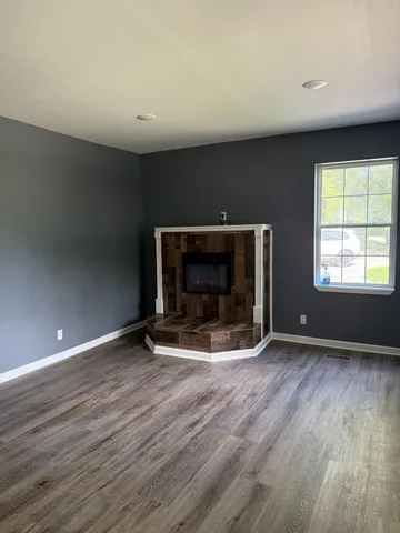 an empty room with wooden floor and fireplace