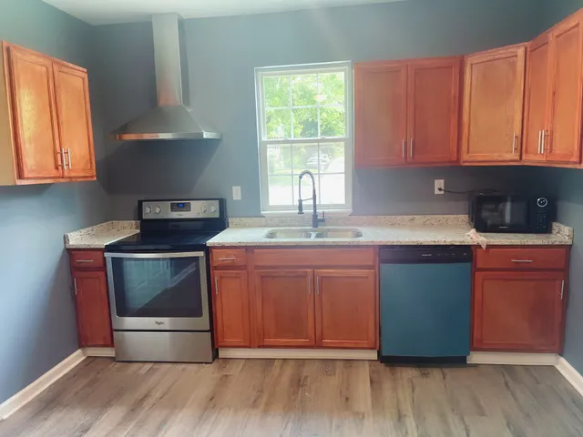 a kitchen with granite countertop wooden cabinets a sink and a stove with wooden floor