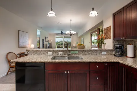 a kitchen with granite countertop a sink cabinets and wooden floor