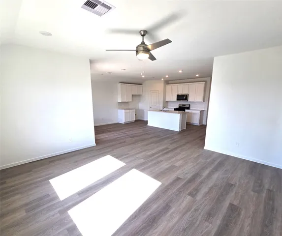 a view of a kitchen with wooden floor and a ceiling fan