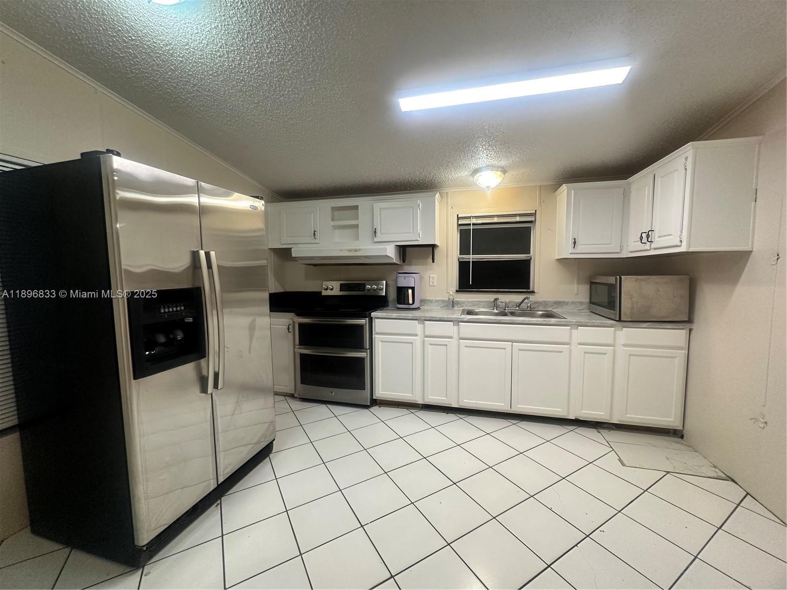 22844 Tradewind Road, Unit H Boca Raton, FL 33428 - Photo 3 of 16 a kitchen with stainless steel appliances a refrigerator sink and white cabinets