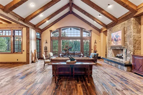 a living room with furniture a fireplace and floor to ceiling windows
