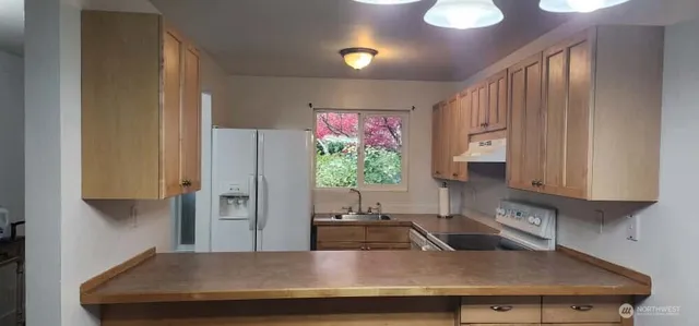 a kitchen with stainless steel appliances granite countertop a sink a refrigerator and a stove