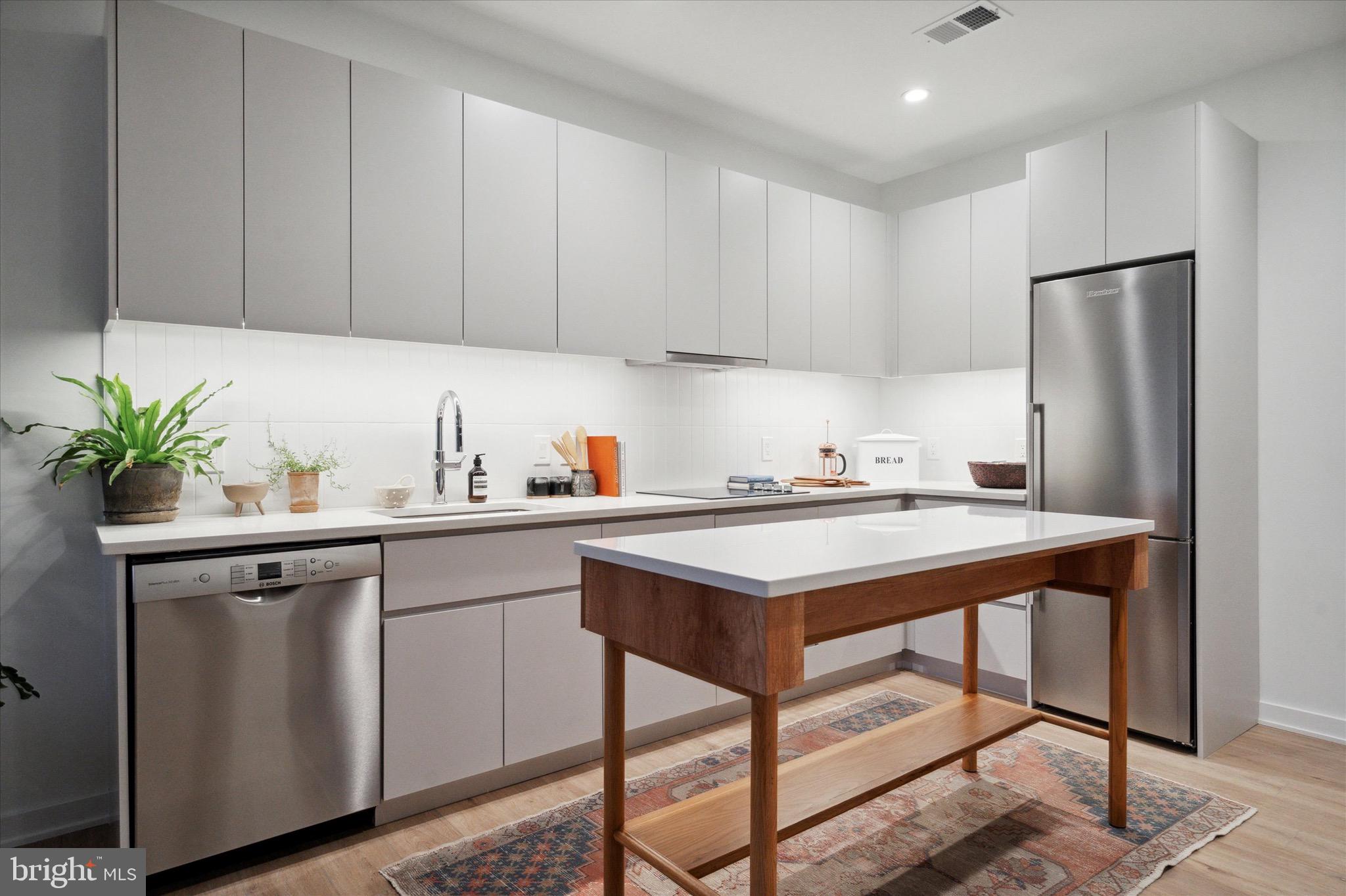 a kitchen with stainless steel appliances a sink a refrigerator and cabinets
