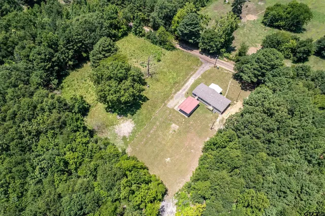 an aerial view of residential house with outdoor space and trees all around